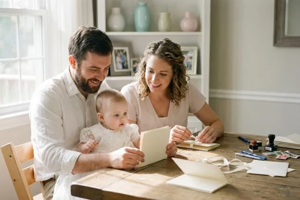 Famille heureuse préparant des invitations de baptême à la maison