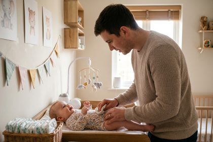 Jeune papa change la couche de sa fille dans une nurserie
